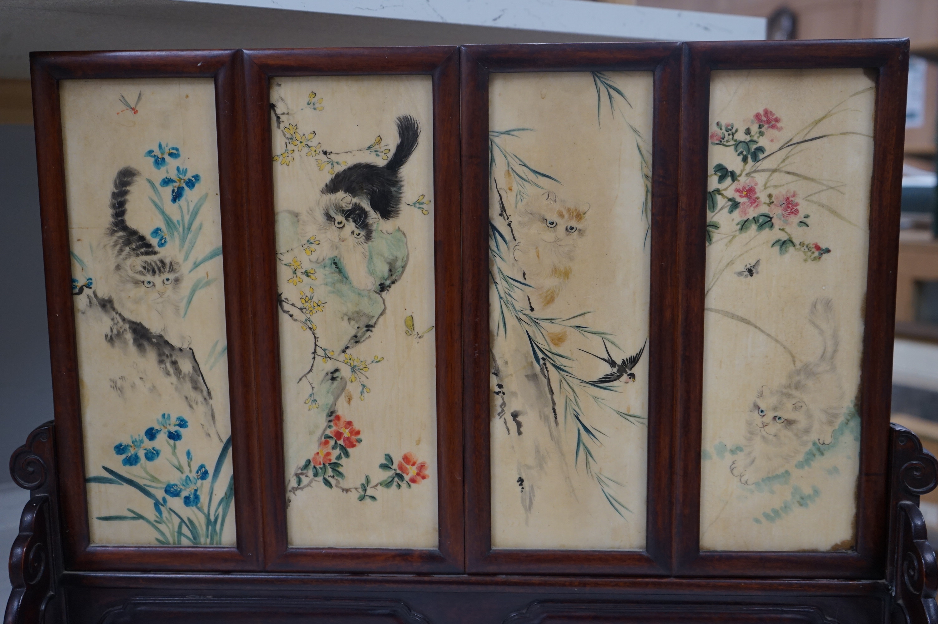 A Chinese four painted porcelain panel and carved hardwood table screen, 54cm wide x 42.5high. Condition - fine staining to one panel and top carved panel of screen missing